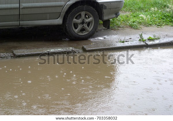 A parked car,\
its lower part with wheels, next to a large puddle on which the\
bubbles are from the rain. Summer, early autumn, damp, rainy. Do\
not go to the car, the\
problem.