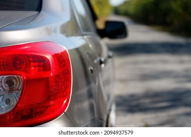 A Parked Car On A Road Leading Away Into The Distance. The Back Of The Car Is A Plafond Of Lighting