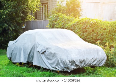 A parked car with protective cover in wet weather