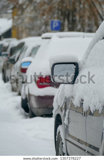 Parked\
cars covered with snow. City street in the\
winter.