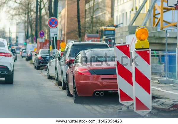 Parked cars in the Dusseldorf street. Maintenance\
sign on the road