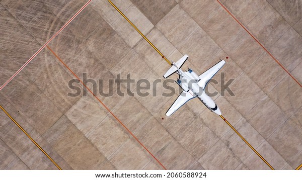 Parked expensive\
private airplane on concrete ground of airport, aerial. Small\
business jet parked on the\
runaway