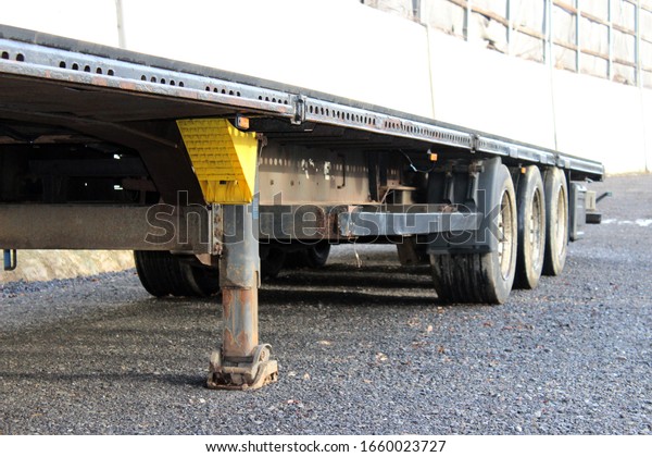Parked\
semi trailer, side view, parked on a gravel\
yard