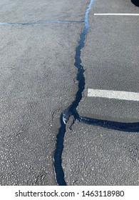 Parking Lot With Black Tar Filling The Cracks