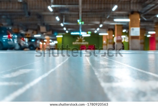 Parking lot cars blurred. Car lot parking\
space in underground city garage. Empty road asphalt background in\
soft focus. Industrial Shed or Parking\
Lot.