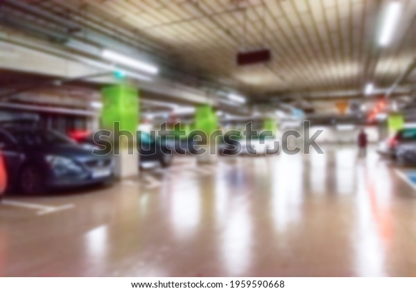 Parking lot cars blurred. Car lot parking\
space in underground city garage. Empty road asphalt background in\
soft focus. Industrial Shed or Parking\
Lot