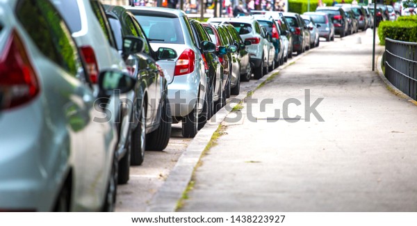 Parking of cars near the\
sidewalk for pedestrians, the cars stand in row on Parking in the\
old town.