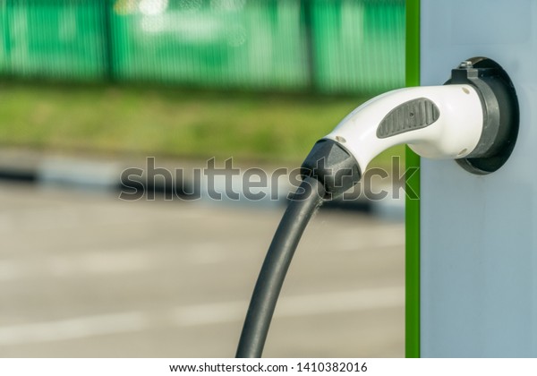 Parking with charging station electric car\
on a city street. Closeup of car charging\
cable