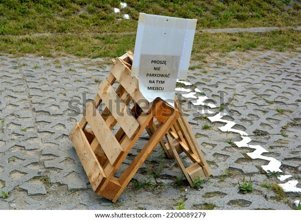 Parking clogged with pallets with a sheet of paper in\
Polish with a parking\
ban