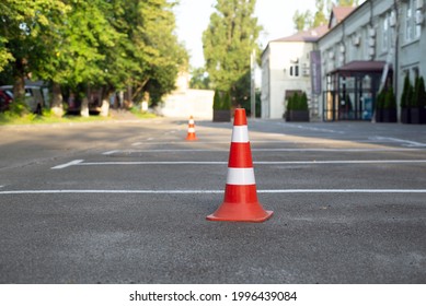 parking cone on the asphalt. Plastic orange parking cone standing in the street. Orange and white road cone for parking, selective focus. Parking cones  - Powered by Shutterstock