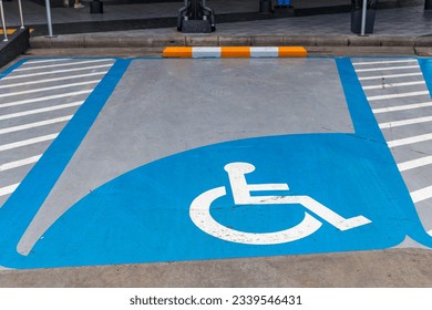 Parking for disabled or wheelchair. A sign indicates reserved parking for disabled people in a car park. International handicapped symbol painted in bright blue on a shopping center parking space.