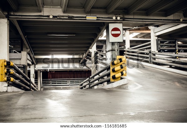 Parking garage in basement,\
underground interior and stop sign, construction technology steel\
and concrete Neon light in bright industrial\
building.