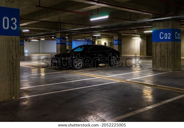 Parking garage interior with\
a few parked cars. Underground parking garage in Bucharest,\
Romania, 2021