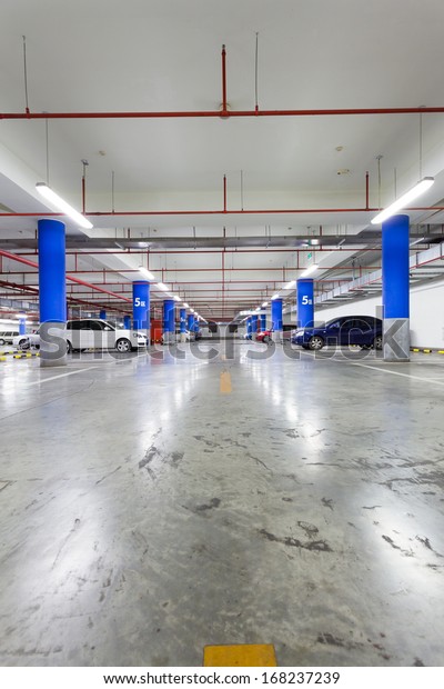 Parking garage, underground interior with a few\
parked cars