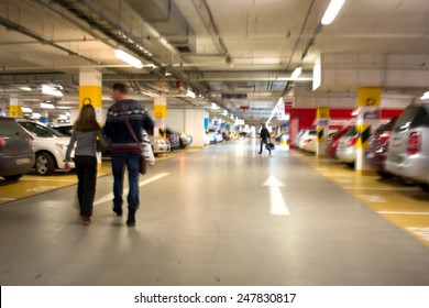Parking garage, underground interior with a parked cars and people. Intentional motion blur