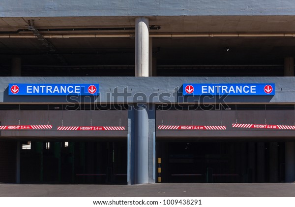 Parking garages entrance gates\
at shopping mall for cars vehicles from outdoors road with\
signs.