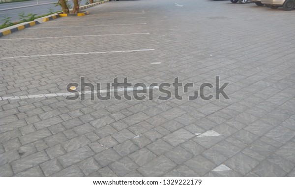 Parking lane on\
interlocking tiles and covered by curb ( kerb ) stones and marked\
by white paint for car\
parking
