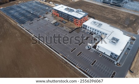 A parking lot with a large building in the background. The parking lot is empty and the building is in the process of being built