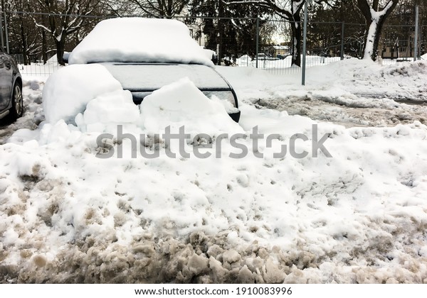 In the parking lot, the car is snowy and\
barricaded with pieces of snow in\
winter