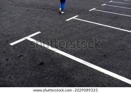 parking markings on the asphalt, women's feet are walking on the asphalt. empty parking spaces. white markings on the road.