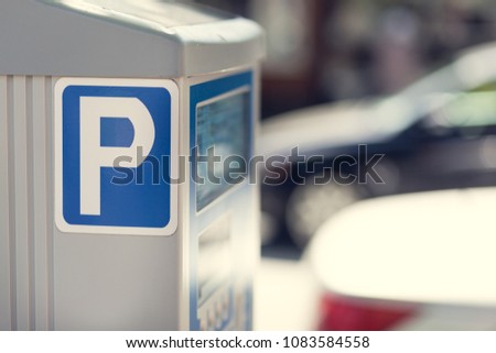 Parking meter and background cars with a depth of field.