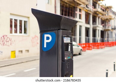 Parking meter with solar panel on a narrow street with a construction site nearby