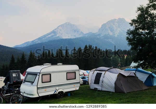 Parking in a mountain camping. Cars with roof tent,\
camper, tourist tent with beautiful mountain view on background -\
Savin Kuk mount in