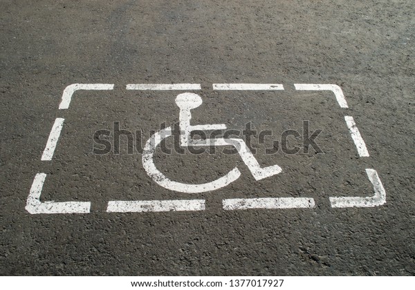 Parking lot\
with painted sign of wheelchair on asphalt, parking spaces for\
disabled visitors. Disabled parking\
spaces.