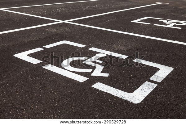 Parking places with handicapped or disabled signs\
and marking lines on\
asphalt