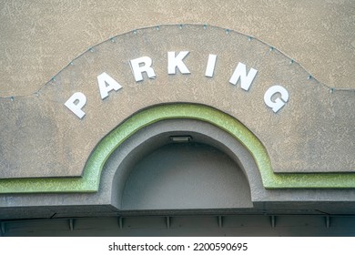 Parking sign on the wall above the arched entrance at downtown Tucson, Arizona. Painted gray concrete wall with parking letters with stringlights above the letters.