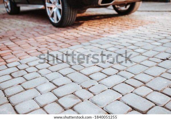 Parking space for a car in the yard of a stone\
tile house - paving\
stones