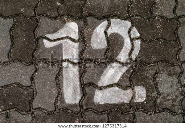 Parking space number painted\
on a paving stone. Parking signs for passenger cars. Season of the\
autumn