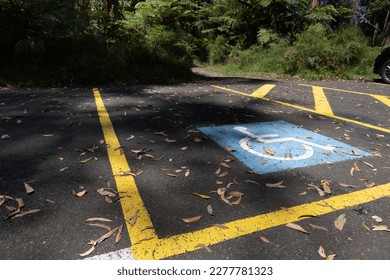 Parking space reserved for the disabled in a forest near Melbourne, Australia. Wheelchair sign on asphalt surrounded by yellow stripes