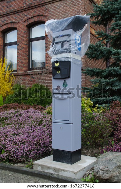 parking ticket\
machine out of operation covered with a plastic bag standing in\
front of a town house in\
germany