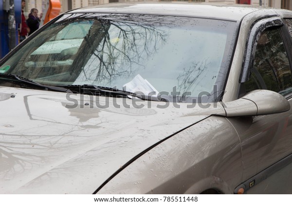 Parking Ticket placed under the wiper blade on\
the windscreen of an illegally parked car. parking ticket placed\
under windshield wiper of a\
car