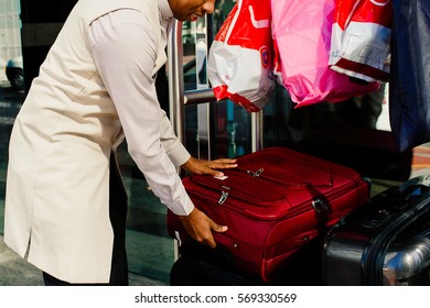 Parking Valet Helps To Take Red Suitcase For The Carriage