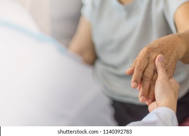 Parkinson And Alzheimer Female Senior Elderly Patient Hand With Physician Doctor Exam In Hospice Care Room.