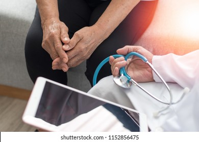 Parkinson And Alzheimer Female Senior Elderly Patient With Doctor Caregiver In Hospice Care. Old Woman Holding Hand And Doctor Physician With Tablet Digital Healthcare And Stethoscope.