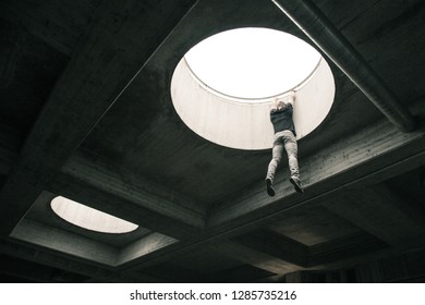 Parkour Athlete Hanging From A Roof Top Hole