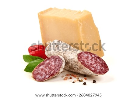 Parmesan block with smooth, yellow texture, cured salami with mold, basil, tomatoes, and pepper, isolated on white background.