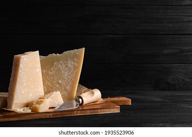 Parmesan Cheese With Board And Knife On Black Wooden Table. Space For Text