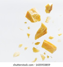 Parmesan Cheese Flying In Different Directions With Crumbs On A White Background With Space For The Text. 