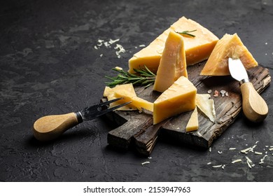 Parmesan cheese on a wooden board, Hard cheese, rosemary and cheese knife on a dark background. place for text, top view. - Powered by Shutterstock