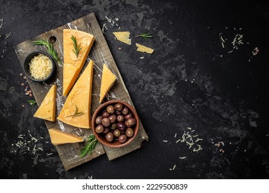 Parmesan cheese on a wooden board, Hard cheese, olives, rosemary on a dark background. place for text, top view, - Powered by Shutterstock