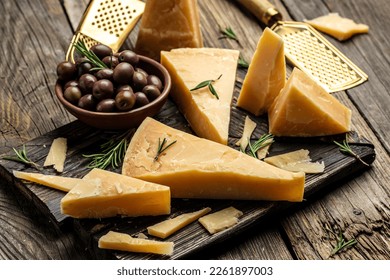 Parmesan cheese on a wooden board, Hard cheese, olives, rosemary and metal grater. place for text, top view, - Powered by Shutterstock