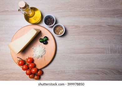Parmesan cheese on a wooden board and cherry tomatoes, olive oil, spices.