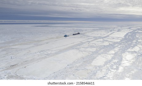 PARNU, ESTONIA - Feb 27, 2022: Aerial View To The Ice Breaker Assisting Cargo Ship To Reach The Harbor Via Waterway Through  The Frozen Sea Bay