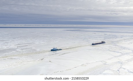 PARNU, ESTONIA - Feb 27, 2022: Aerial View To The Ice Breaker Assisting Cargo Ship To Reach The Harbor Via Waterway Through  The Frozen Sea Bay