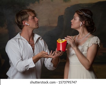 Parody Of The Old, Concept. Cute Young Couple In 18th And 19th Century Style, Listening To Modern Music And Eating Fast Food