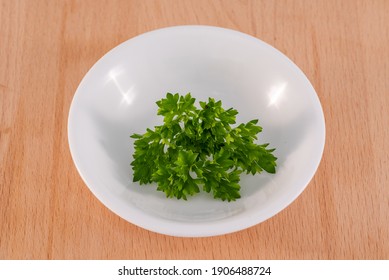 Parsley  herb with curly leaf placed in a white bowl with chopping board background